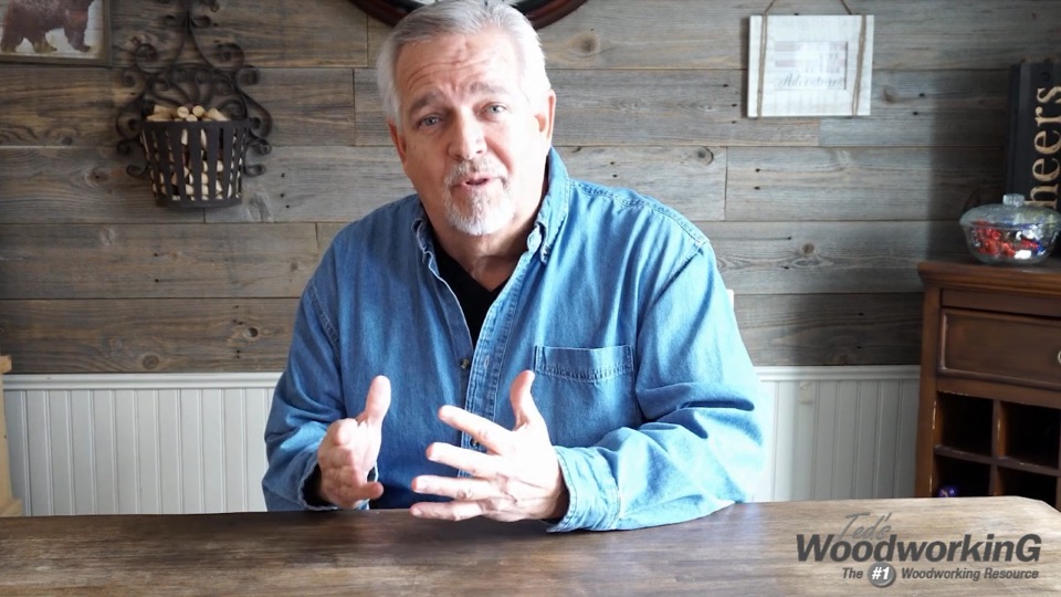 Barry speaking at a wooden table in front of a barn-wood wall